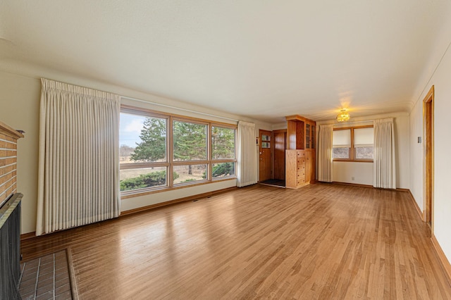 unfurnished living room with baseboards, a fireplace, and light wood-type flooring