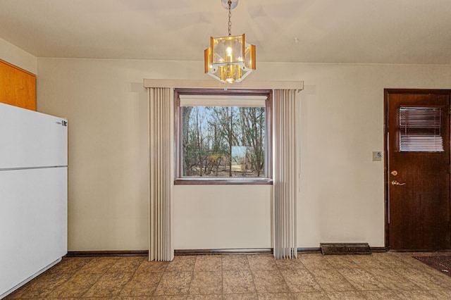 unfurnished dining area featuring baseboards and a chandelier