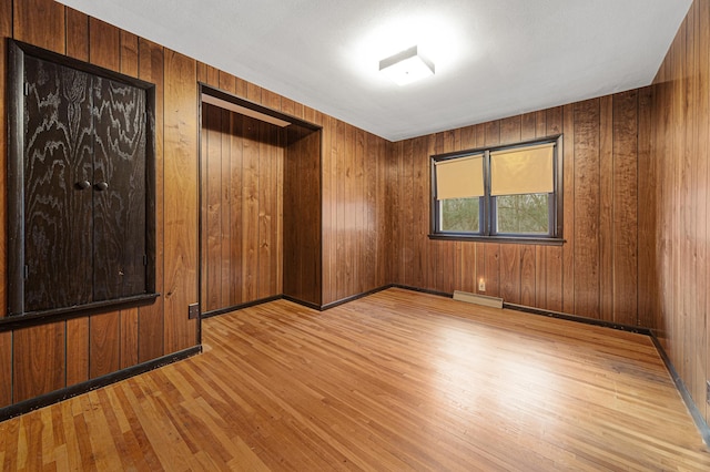 unfurnished room featuring baseboards, visible vents, wood finished floors, and wood walls