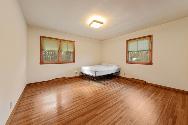 unfurnished bedroom with hardwood / wood-style floors and baseboards