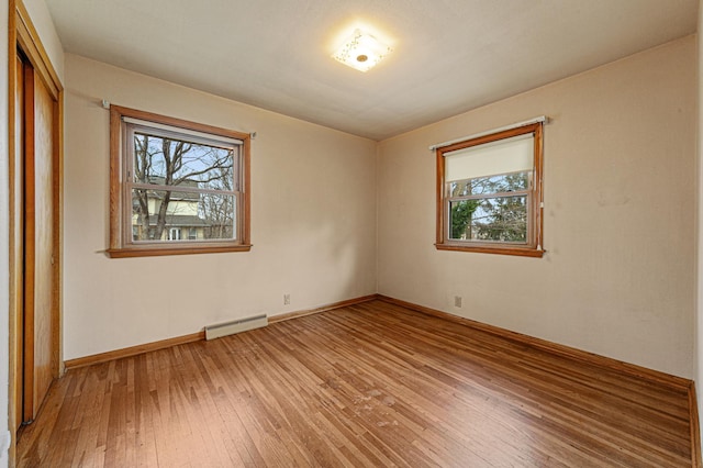 unfurnished room with a baseboard radiator, light wood-style flooring, and baseboards