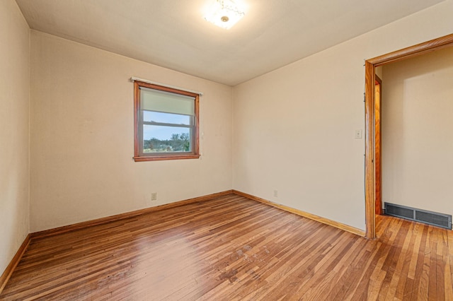 spare room with hardwood / wood-style flooring, baseboards, and visible vents