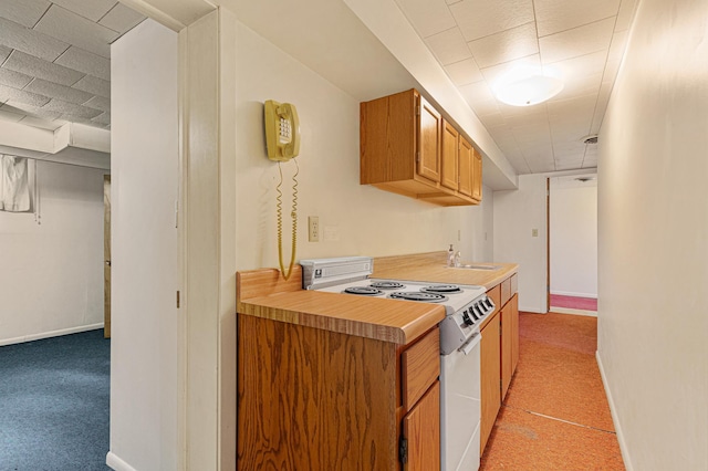 kitchen featuring electric stove, a sink, light countertops, and light carpet