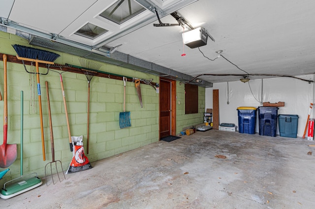 garage with a garage door opener and concrete block wall