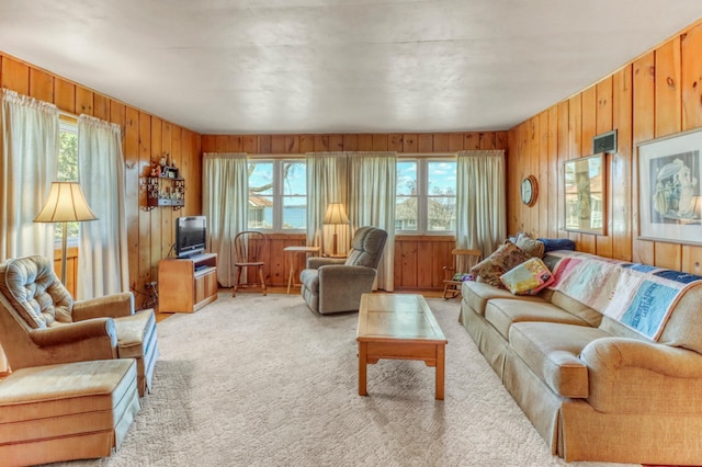 living area with plenty of natural light, wooden walls, and light colored carpet