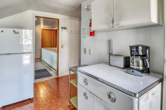 kitchen featuring light countertops, white cabinets, freestanding refrigerator, and a toaster