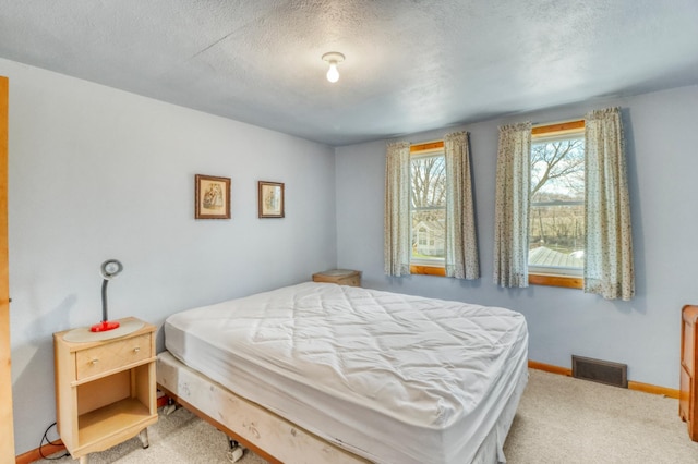 carpeted bedroom featuring visible vents, a textured ceiling, and baseboards