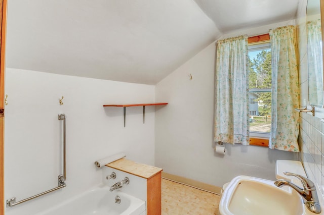bathroom with a sink, a bathing tub, and vaulted ceiling