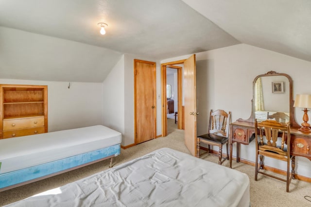 bedroom with baseboards, vaulted ceiling, and light colored carpet