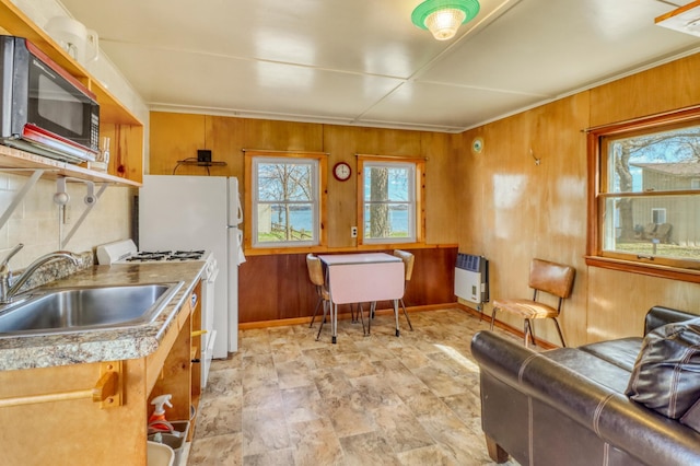 kitchen featuring a sink, wood walls, white gas range, baseboards, and heating unit