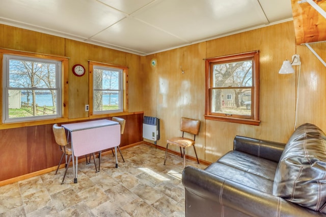 living area with heating unit, baseboards, and wooden walls
