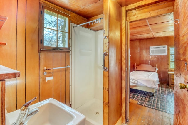 ensuite bathroom with a shower stall, a wall mounted air conditioner, a sink, ensuite bathroom, and hardwood / wood-style floors