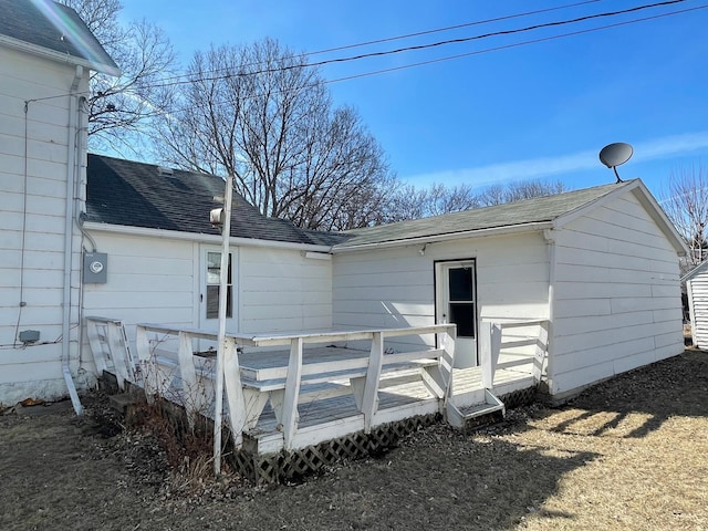 back of property with a deck and roof with shingles
