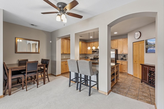294 Spring St, Saint Paul, MN 55102 - kitchen featuring appliances with stainless steel finishes, arched walkways, a kitchen breakfast bar, ceiling fan, and light carpet