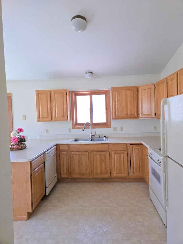 kitchen with a peninsula, white appliances, light floors, light countertops, and a sink