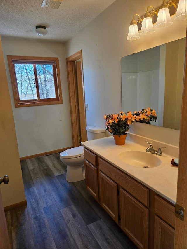 bathroom with vanity, visible vents, wood finished floors, toilet, and a textured ceiling