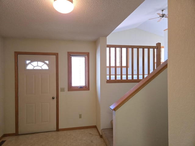 entryway featuring a ceiling fan, a textured ceiling, visible vents, vaulted ceiling, and baseboards