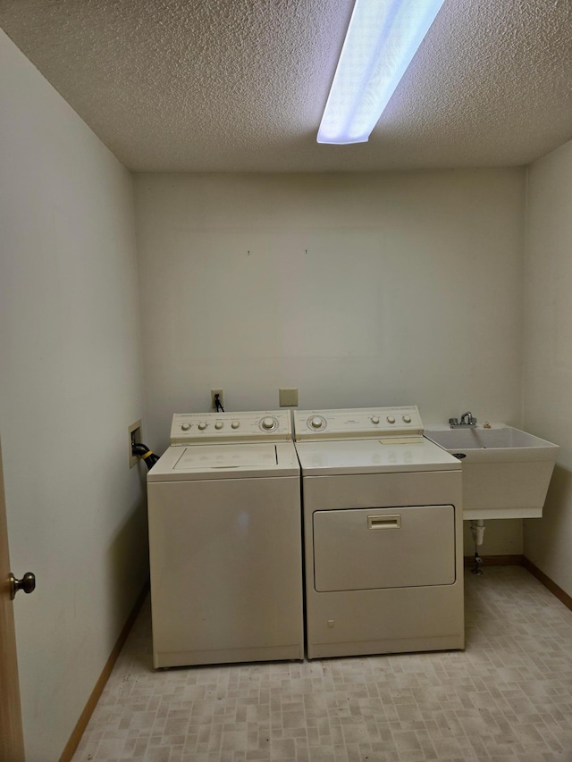 laundry room featuring baseboards, laundry area, a textured ceiling, and washing machine and clothes dryer