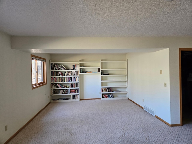 carpeted spare room with visible vents, a textured ceiling, and baseboards