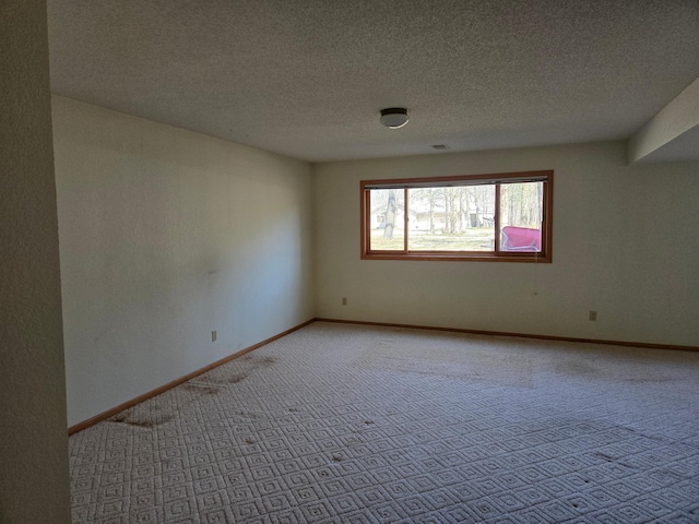 carpeted empty room featuring a textured ceiling and baseboards