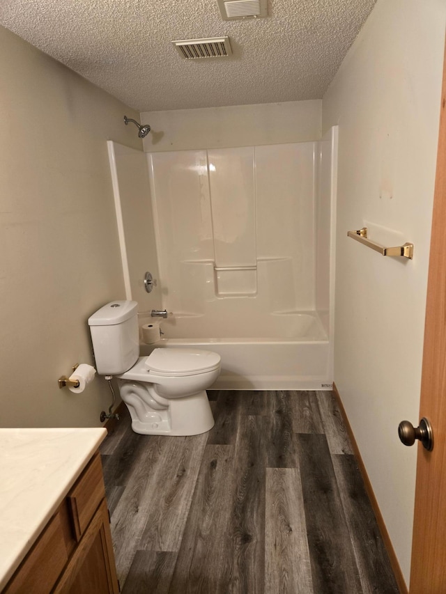 bathroom with visible vents, vanity, wood finished floors, toilet, and a textured ceiling