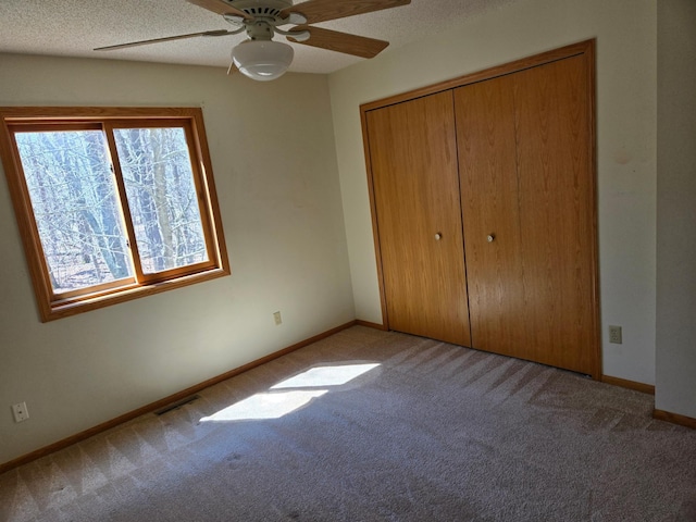 unfurnished bedroom with carpet floors, baseboards, visible vents, and a closet