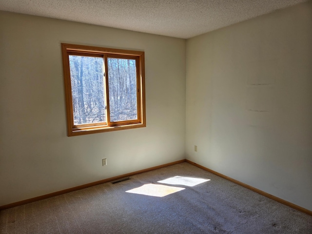 carpeted spare room featuring baseboards, a textured ceiling, and visible vents