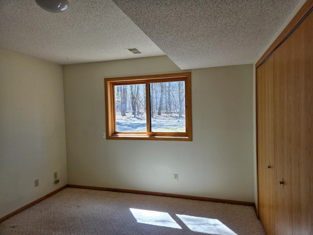 unfurnished bedroom with light colored carpet, a textured ceiling, visible vents, and a closet