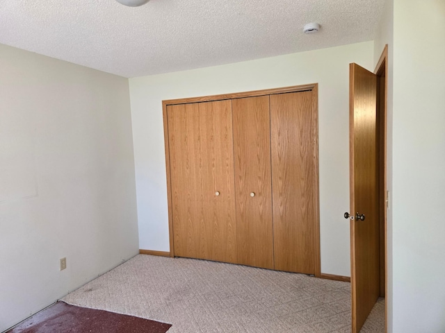 unfurnished bedroom with carpet floors, a closet, and a textured ceiling