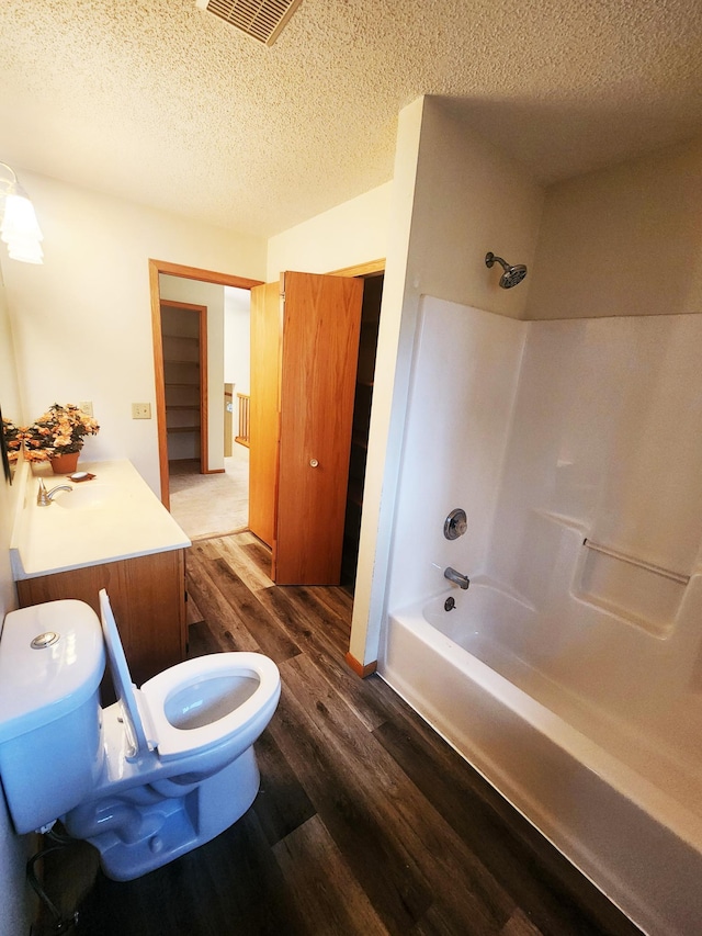 14595 Lynndale Ln, Baxter, MN 56425 - bathroom featuring toilet, wood finished floors, bathtub / shower combination, a textured ceiling, and visible vents