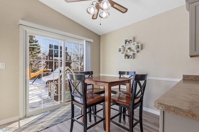 dining area with baseboards, lofted ceiling, wood finished floors, and a ceiling fan