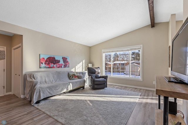 living room featuring baseboards, lofted ceiling with beams, wood finished floors, and a textured ceiling