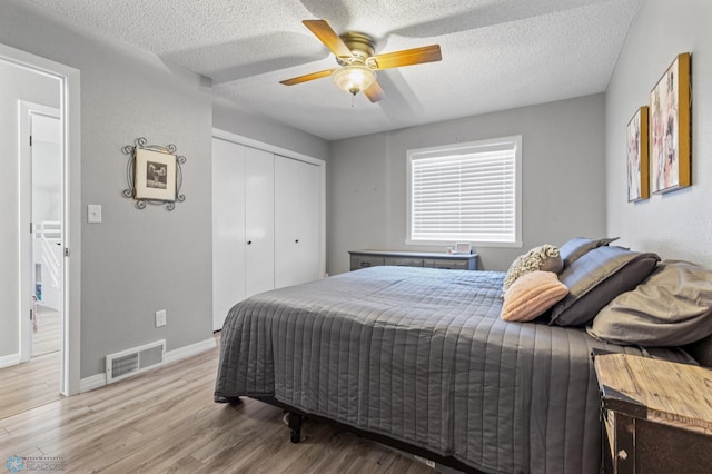 bedroom featuring a closet, a textured ceiling, visible vents, baseboards, and light wood-type flooring