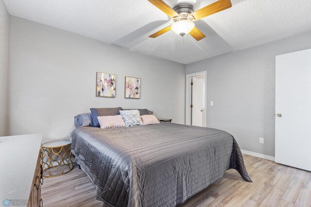 bedroom with baseboards, light wood-style floors, ceiling fan, and a textured ceiling