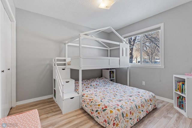 bedroom featuring baseboards, a textured ceiling, and light wood-type flooring