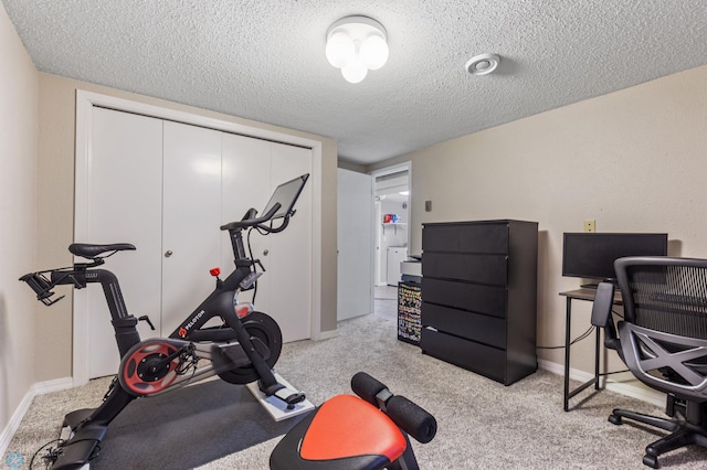 exercise room with baseboards, carpet, and a textured ceiling