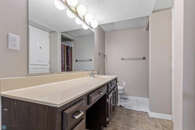 full bath featuring tile patterned floors, toilet, vanity, a textured ceiling, and baseboards