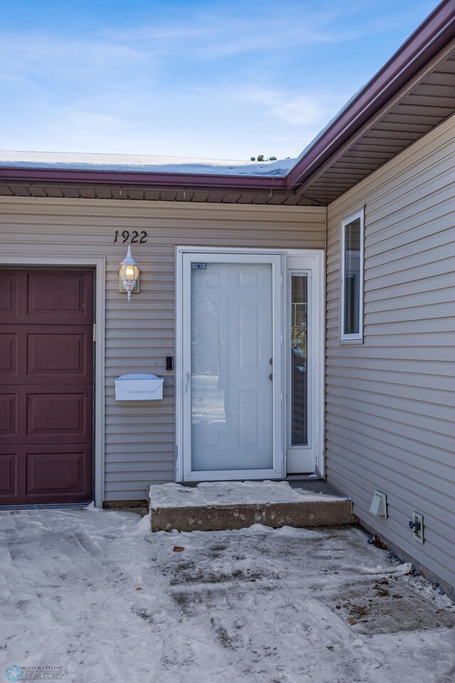 snow covered property entrance with a garage
