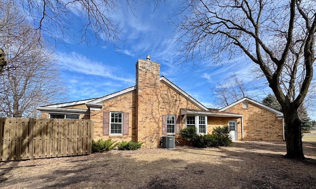 view of side of property featuring a chimney, fence, and brick siding