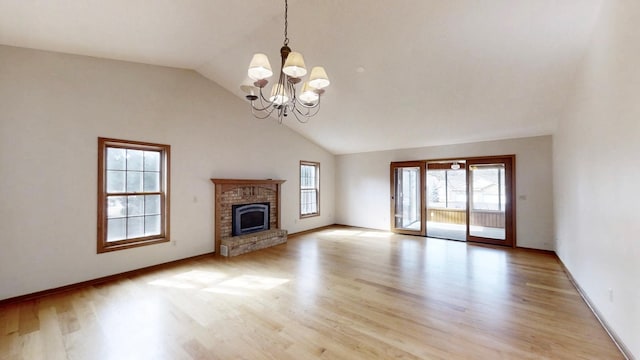 unfurnished living room featuring high vaulted ceiling, a chandelier, a fireplace, light wood-style flooring, and baseboards