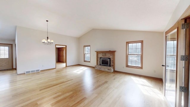 unfurnished living room featuring visible vents, a chandelier, a brick fireplace, lofted ceiling, and light wood-type flooring