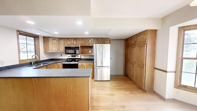 kitchen featuring a healthy amount of sunlight, a sink, appliances with stainless steel finishes, and a peninsula
