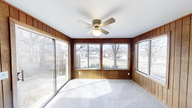 unfurnished sunroom with carpet flooring and wooden walls