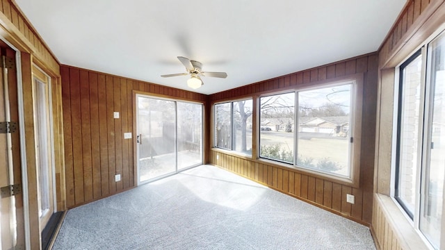 unfurnished sunroom with carpet and wooden walls