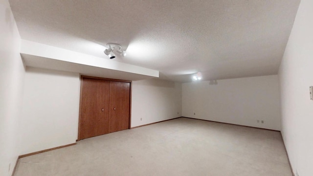 interior space with baseboards, a textured ceiling, and light carpet