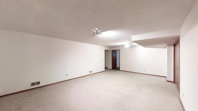 unfurnished room featuring baseboards, a textured ceiling, visible vents, and light colored carpet
