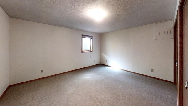 unfurnished room featuring carpet, baseboards, and a textured ceiling