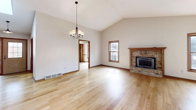 unfurnished living room with visible vents, a brick fireplace, lofted ceiling, light wood-type flooring, and an inviting chandelier