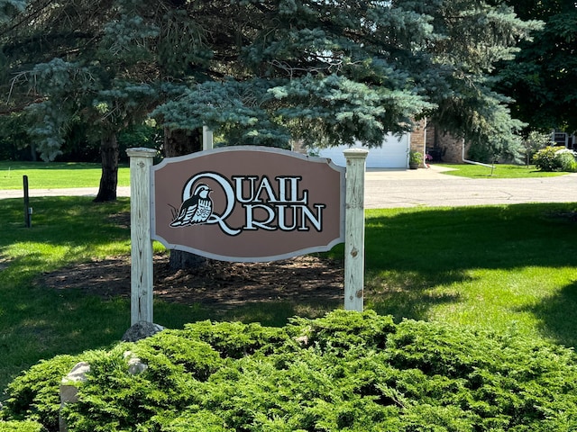 community sign with driveway and a yard