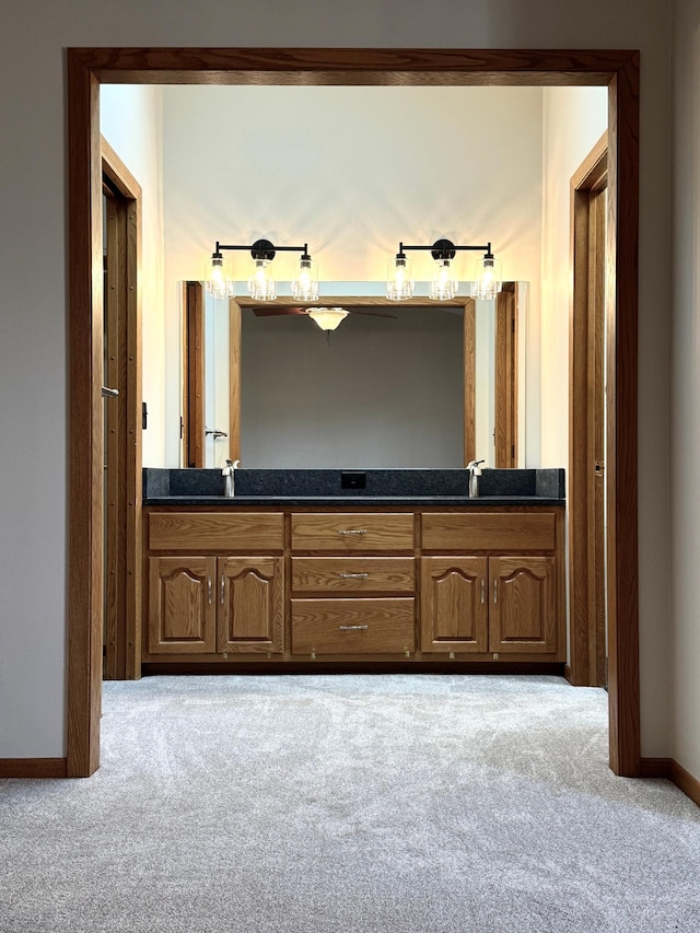 full bathroom featuring carpet flooring, a sink, baseboards, and double vanity